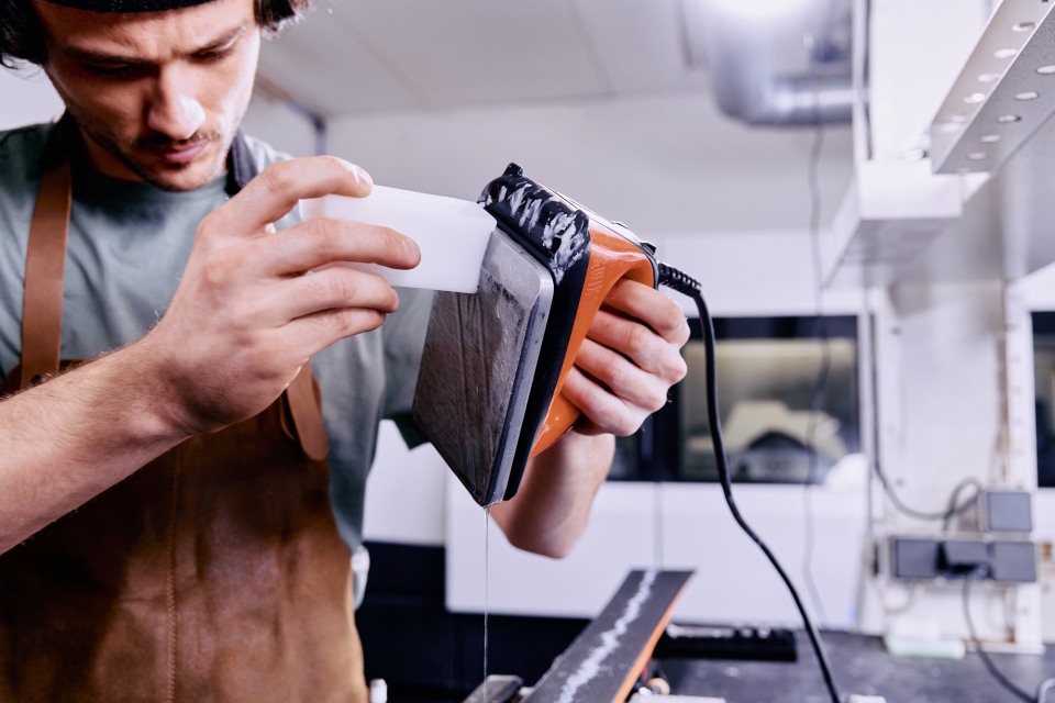 Mann trägt Skiwachs mit einem Bügeleisen auf einen Ski auf, um die Oberfläche für bessere Gleiteigenschaften zu präparieren.